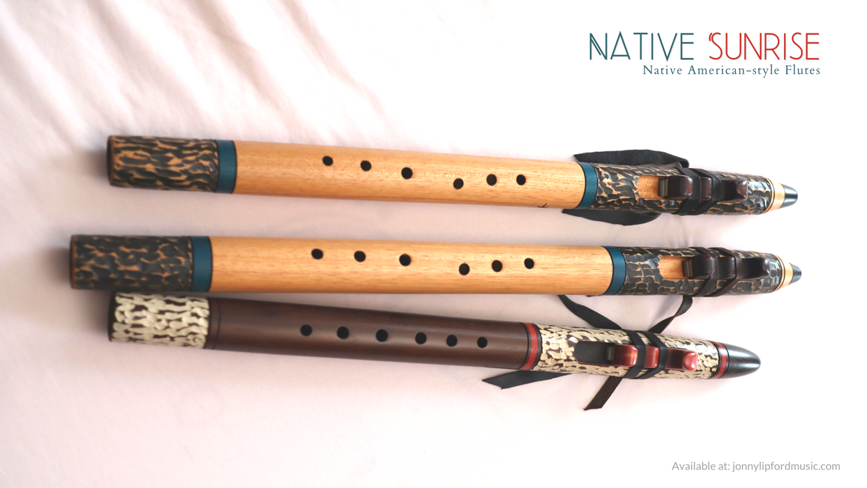 Native American flutes laying side-by-side which shows the offset fingering holes of the two large bass native american flutes